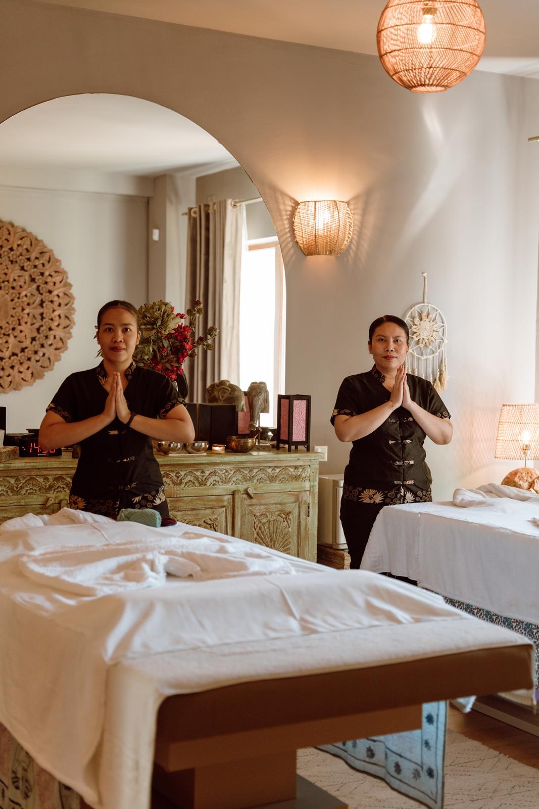 Două terapeute în salutul namaste, într-o cameră de masaj luminoasă